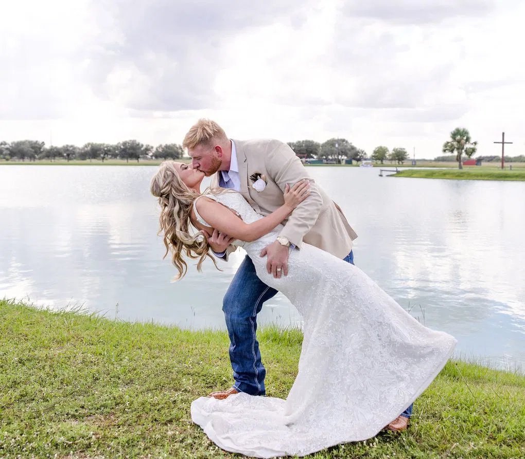 Bride and groom kiss by the lake